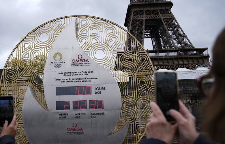 Tourists picture the countdown clock reading 100 days before the Paris 2024 Olympic Games opening ceremony, Wednesday, April 17, 2024 in Paris. The Paris 2024 Olympic Games will run from July 26 to Aug. 11. (AP Photo/Christophe Ena) PAR101 PAR101