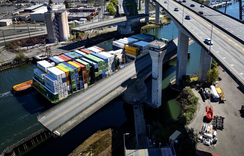 The Spokane Street Bridge, left, has swung open for a barge carrying containers, seen from the air, Sunday, April 14, 2024 in Seattle. The bridge, which crosses the Duwamish Waterway, will close April 19-28 to people driving, walking, and biking for a complete upgrade to the bridge’s control and communications system. At center is the control tower and to the right is the West Seattle Bridge.