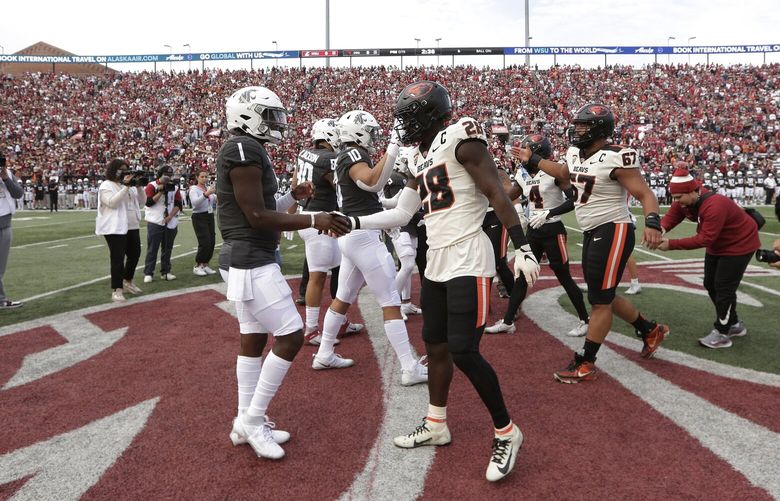 Washington State quarterback Cameron Ward (1), Oregon State defensive back Kitan Oladapo (28) and other members of their teams greet each other during the coin toss before an NCAA college football game, Saturday, Sept. 23, 2023, in Pullman, Wash. (AP Photo/Young Kwak)