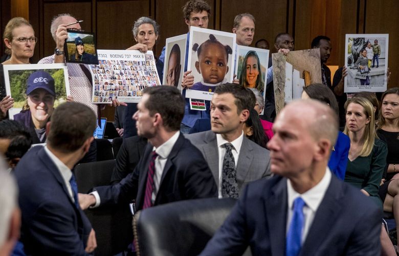 Boeing Company President and Chief Executive Officer Dennis Muilenburg, right foreground, watches as family members hold up photographs of those killed in the Ethiopian Airlines Flight 302 and Lion Air Flight 610 crashes during a Senate Committee on Commerce, Science, and Transportation hearing on ‘Aviation Safety and the Future of Boeing’s 737 MAX’ on Capitol Hill in Washington, Tuesday, Oct. 29, 2019. (AP Photo/Andrew Harnik)