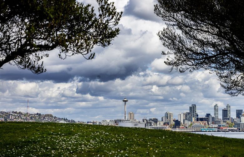 The Space Needle, downtown and big clouds are the backdrop along Alki Trail as spring weather abounds, Sunday, April 21, 2024 in West Seattle.