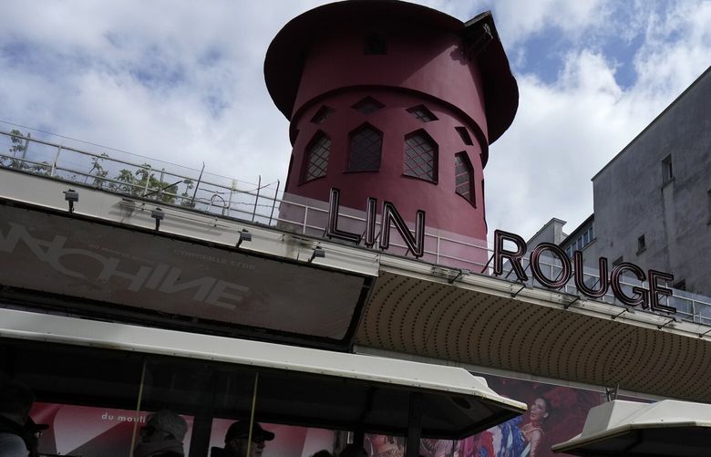 A tourists train drives past the Moulin Rouge (Red Mill) Thursday, April 25, 2024 in Paris. The windmill from the Moulin Rouge, the 19th century Parisian cabaret, has fallen off the roof overnight along with some of the letters in its name. (AP Photo/Thibault Camus) PAR115 PAR115