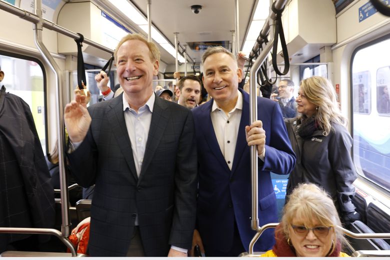 Microsoft Vice Chair and President Brad Smith, left, and King County Executive Dow Constantine take the Eastside light rail 2 line from the Bellevue Downtown Station to the Redmond Technology Station on Saturday.  (Karen Ducey / The Seattle Times)