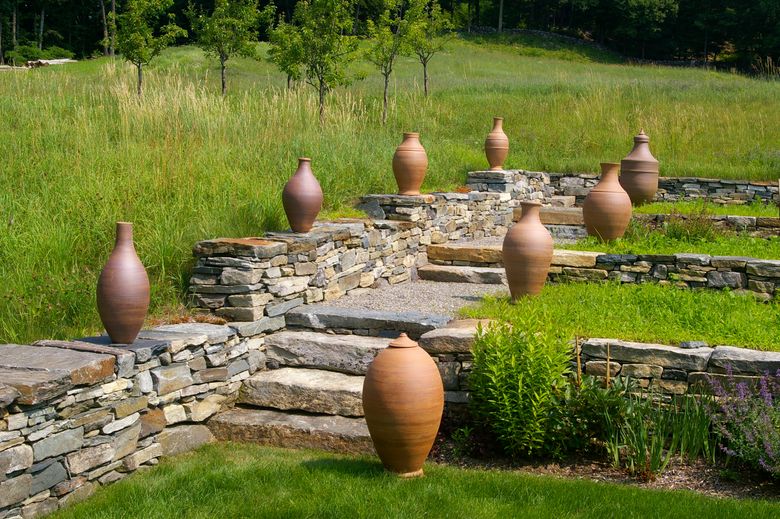 A collection of Stephen Procter’s stoneware pots flank a stone staircase at a private home in Guilford, Vt. An imposing work of pottery can be as important to the design of a landscape as any well-placed plant. (Stephen Procter via The New York Times)