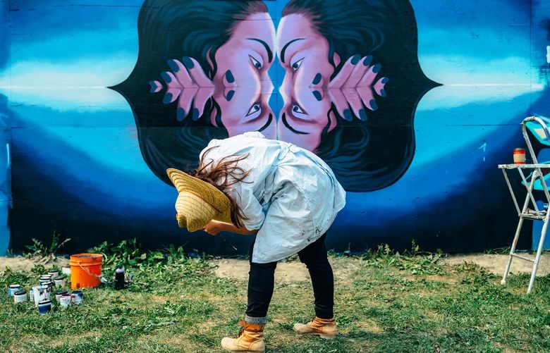 A woman leans over while looking at a colorful abstract mural.