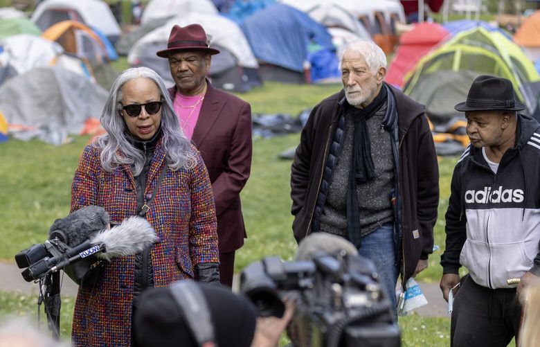 Maisha Barnett speaks about conditions at Powell Barnett Park as asylum seekers camp there on Monday, May 6, 2024, in Seattle. Barnett was flanked by Robert Henry, left, John Barber and Eric Barnett.