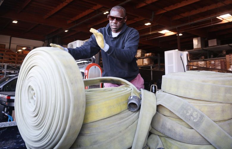 Wangi Mugenyi, from Lynnwood, arranges a pallet of used firehoses he bought at a city owned warehouse in Seattle on Thursday, April 18, 2024. The hoses from the Seattle Fire Department can no longer handle high pressure water without leaking but Mugenyi will send them to Uganda where they can be used to pump water.