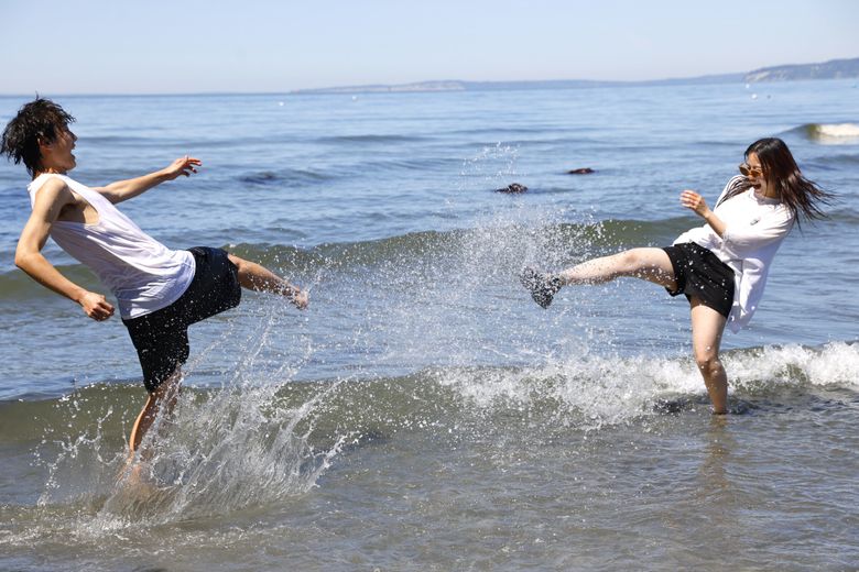 Haruto Terada, left, and Kirara Fukuzawa, right, both from Japan and studying abroad at Edmonds College, enjoy the weather and low tides in Edmonds on Friday. (Karen Ducey / The Seattle Times)