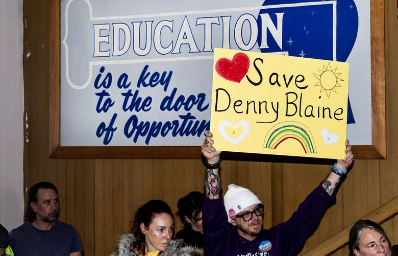 People hold signs during a community hearing in opposition to an anonymous donation towards a play structure at Denny Blaine Park Wednesday, Dec. 6, 2023, at MLK Fame Community Center in Seattle.