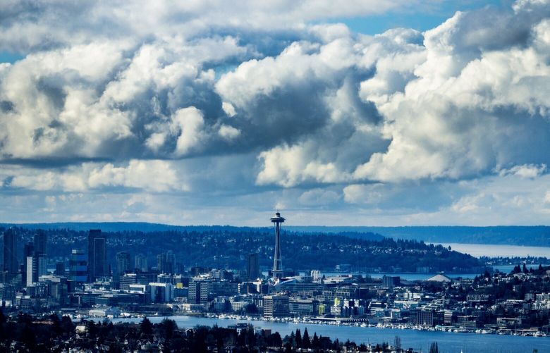 With Lake Union in the foreground, a photo taken with a telephoto lens on a drone flying at little under 400 feet above NE Seattle shows the Space Needle with bluebird skies and plenty of pillow-like clouds, Thursday, Feb. 22, 2024 in Seattle.