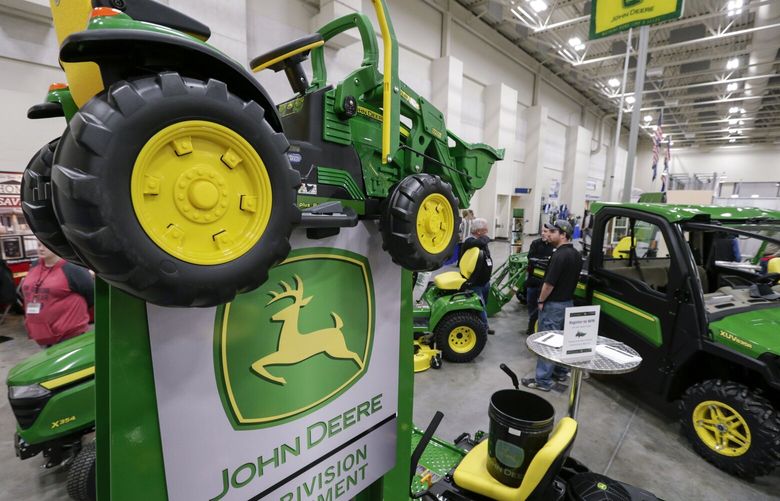 FILE – In this Feb. 23, 2018 file photo, John Deere products, including a toy tractor on the sign, are on display at the “Spring into Spring” home and garden trade show in Council Bluffs, Iowa,  Deere & Co. posted strong quarterly results, but shares slid early after the agricultural machinery company cut its forecast for 2024 in what is expected to be a tight year for farmers. (AP Photo/Nati Harnik, FIle) NYBZ425 NYBZ425