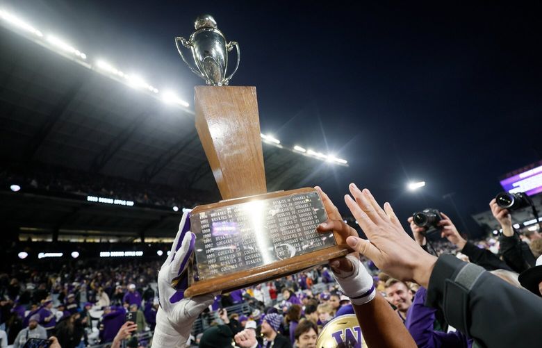 Players hold up the trophy after a 24-21 win over the Cougars in the Apple Cup Saturday, Nov. 25, 2023 in Seattle. 225576