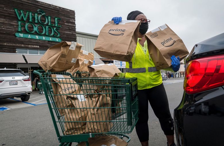 An independent contractor loads grocery bags into a car outside a Whole Foods Market in Berkeley, Calif., in October 2020. (David Paul Morris / Bloomberg, 2020)