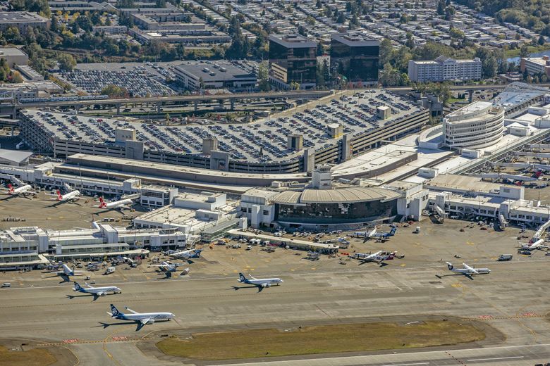NOW: A 2018 aerial view illustrates Sea-Tac’s exponential growth. The boomerang-shaped modern terminal, completed in 1973, was superimposed over the original building. Its 12,000-space parking facility is reputedly the largest covered garage in the world. (Don Wilson / Port of Seattle)