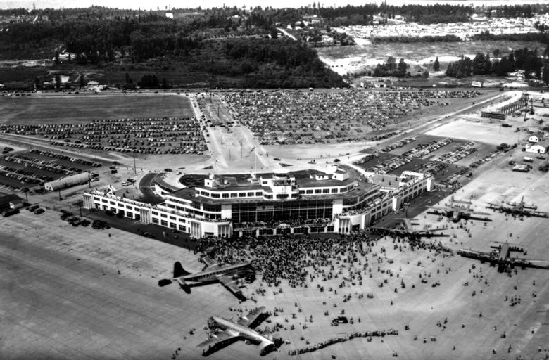 THEN: An aerial photo reveals the footprint of the gleaming terminal/administration building as well as open-air parking for thousands of automobiles, wide runways and room to expand. Eager crowds can be seen touring the facility and parked airliners. (Paul Dorpat Collection)