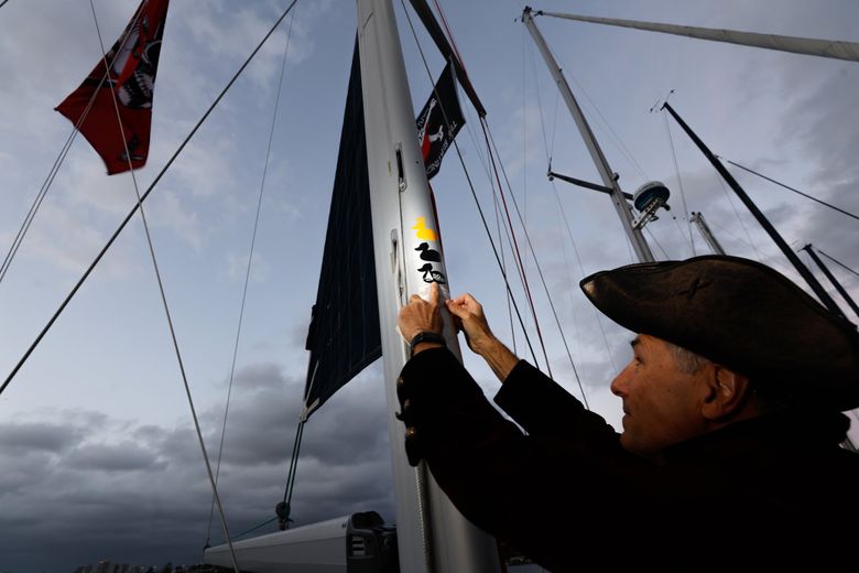 Skipper of the SV Mischief, Mike Panzitta, adds two Duck Dodge stickers on his mast: a bronze one for coming in third in their start, and a Crown Duck special award for community service (on this night, for hosting a Seattle Times photographer). (Karen Ducey / The Seattle Times)