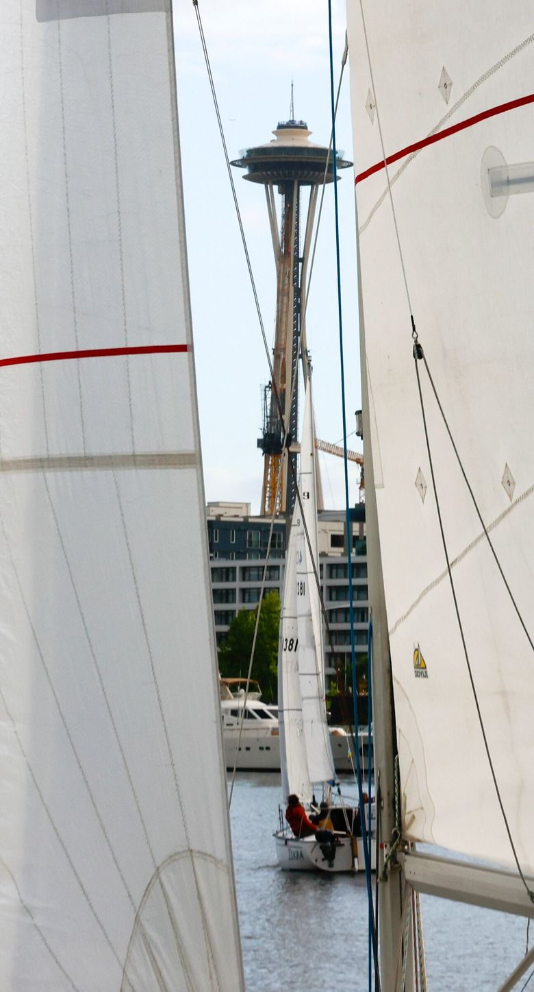 The Space Needle is visible through sails and lines during Duck Dodge, where each week a volunteer-run committee boat anchors in the middle of the lake, checking in boats and handing out stickers at the end. (Karen Ducey / The Seattle Times)