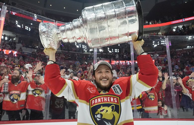 Florida Panthers defenseman Brandon Montour, center, lifts the Stanley Cup trophy after Game 7 of the NHL hockey Stanley Cup Final against the Edmonton Oilers, Monday, June 24, 2024, in Sunrise, Fla. The Panthers defeated the Oilers 2-1. (AP Photo/Wilfredo Lee) OTK OTK