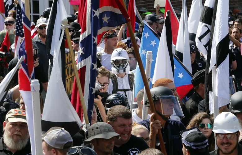 FILE – White nationalist demonstrators walk into the entrance of Lee Park surrounded by counter demonstrators in Charlottesville, Va., Saturday, Aug. 12, 2017. A jury Monday, July 1, 2024, awarded ordered white nationalist leaders and organizations to pay a total of more than $26 million in damages to people who had suffered physical or emotional injuries during the event. (AP Photo/Steve Helber, File) NYWS305 NYWS305