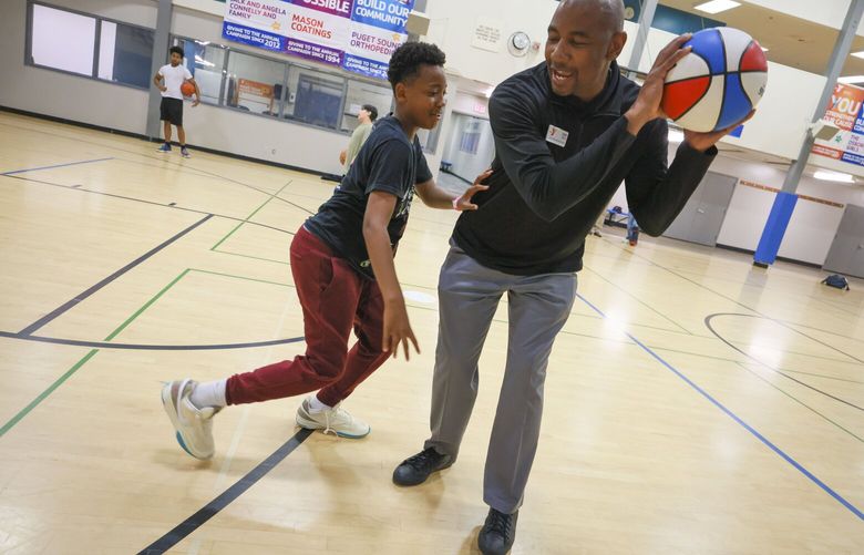 Jordan Lofton, 12, left, and Chris Spivey, right, who is the executive director of the YMCA Center for Community Impact and Diversity, Equity, share a moment while playing basketball during a Tacoma Summer Late Night for youth at the Morgan Family YMCA in Tacoma on Wednesday, June 26, 2024. 

 227336