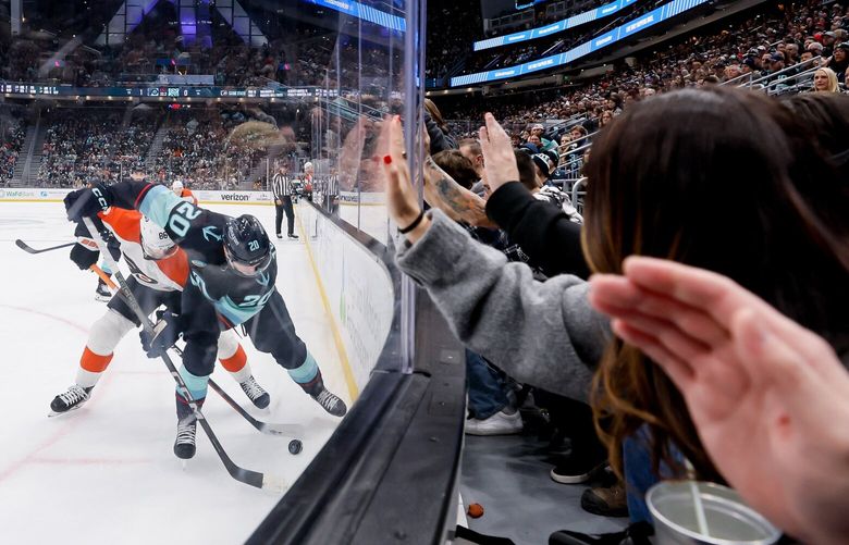 Fans slap the glass as Seattle Kraken right wing Eeli Tolvanen and Philadelphia Flyers left wing Joel Farabee vie for the puck during the second period Friday, Dec. 29, 2023 in Seattle. 225846