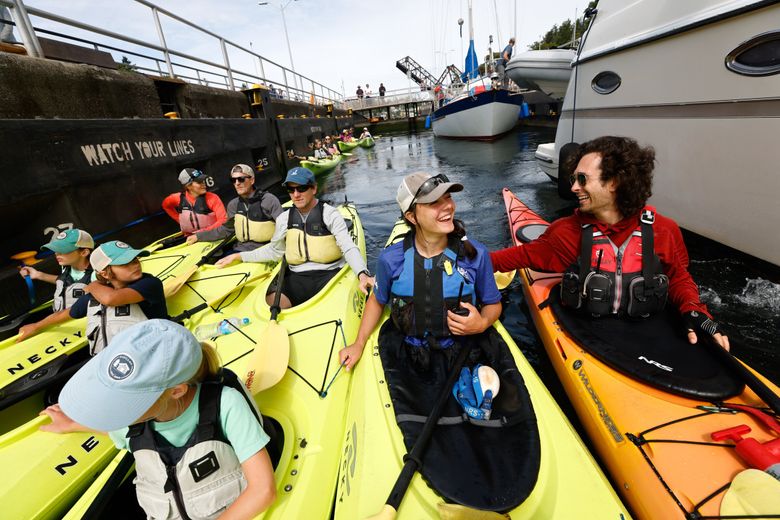 Guides Anna Goddu, center right, and Lindsay Maggard, far right, lead a tour of the Ballard Locks with Ballard Kayak & Paddleboard on June 29. The tour has “something for everybody,” said Maggard, a naturalist guide: wildlife, Seattle history, the Locks themselves, exercise, sunshine. (Karen Ducey / The Seattle Times)