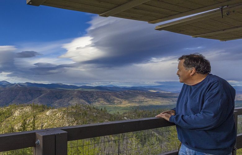 Austin has a keen eye to know the difference between a puff of smoke and a cloud from his perch atop 5,008-foot Leecher Mountain. Here he checks the horizon from the lookout’s catwalk.