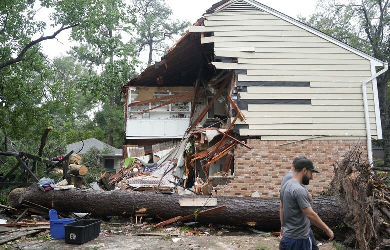 CORRECTION CORRECTS NAME People gather outside a home in the 17400 block of Rustic Canyon Trail where Maria Loredo, 74, died after a tree fell on her second story bedroom during Hurricane Beryl Monday, July 8, 2024, in Houston. (Melissa Phillip/Houston Chronicle via AP) TXHOU253 TXHOU253