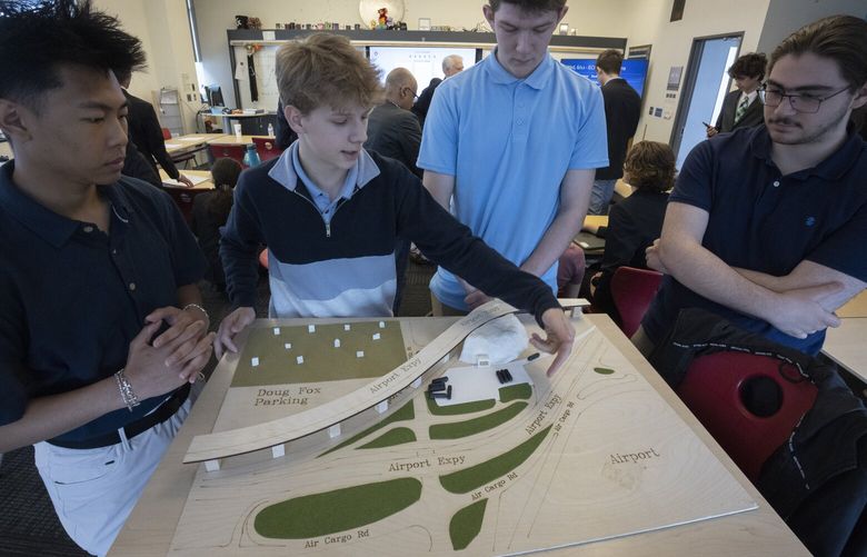 Nicholas Warfield talks about  the studentsâ€™ proposed new cell phone parking structure (left of his fingers) at SEA (Seattle-Tacoma International Airport) after a class presentation Wednesday, June 12, 2024.  Students (l-r) Ethan Vo, Warfield, Corey Crosby and Zafer Kilinc  show the model they made of their idea for a new underground cell phone lot after the presentation they made Wednesday, June 12, 2024.  It is  adjacent to the current cell phone lot, directly in front of the structure, at the airport.

Junior high school students at Raisbeck Aviation High School presented their ideas for how the SeaTac airport can replace its crowded cell phone parking lot as part of their Environmental Challenge Project. Port of Seattle officials and others judged the student presentations at the school  and then decided which team had the best proposal.  227129
