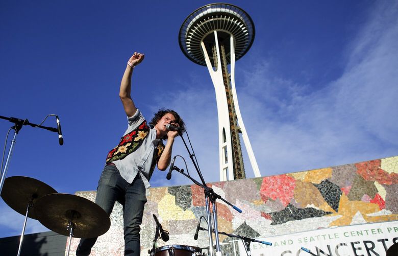 140758– MURAL CONCERT LO — 08/01/2014
Kithkin’s Ian McCutcheon stands on his drumset as he begins a song during the opening night of KEXP’s free concert series at the Mural Ampitheatre in Seattle on Friday, Aug. 1, 2014. Local band Cumulus and soul and R&B singer Charles Bradley also performed. The series continues with concerts on August 8 ,15 and 22.