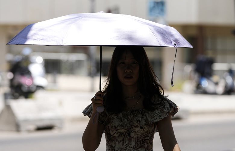 A tourist uses an umbrella to block the sun while she is visiting the downtown of Beirut, Lebanon, Monday, July 15, 2024. (AP Photo/Hassan Ammar) HAS107 HAS107