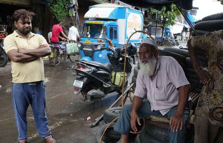 Naushad Ahmed, left, runs a car repair shop that regularly floods. He said the city should spend more on improving basic infrastructure. MUST CREDIT: Gerry Shih/The Washington Post