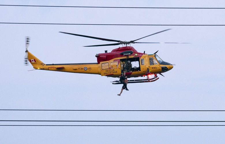 A Royal Canadian Air Force Search and Rescue helicopter crew rescues a man from Etobicoke Creek following heavy rain in Toronto, Tuesday, July 16, 2024. (Arlyn McAdorey/The Canadian Press via AP) AMA108 AMA108