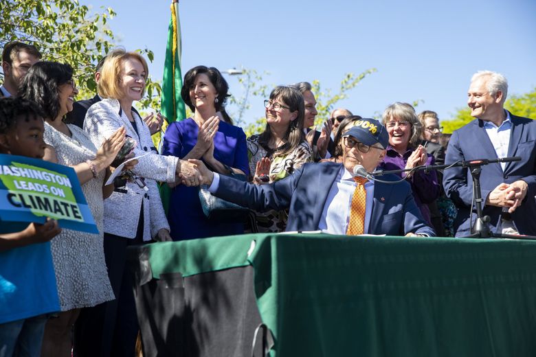 Gov. Jay Inslee shakes the hand of then-Seattle Mayor Jenny Durkan after signing landmark bills in 2019 to wean Washington off fossil fuels. Rising demand from data centers could affect the state’s clean energy plans. (Bettina Hansen / The Seattle Times)