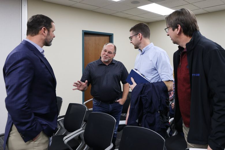 At a meeting of the Grant County Public Utility District commission last fall, Ty Ehrman, left, chief customer officer at Grant PUD, speaks with Chuck Sutton, center left, from REC Silicon; Ryan Beebout, an executive with Sabey; and Matthew Kozma, right, associate director from NTT DATA.  (Karen Ducey / The Seattle Times)