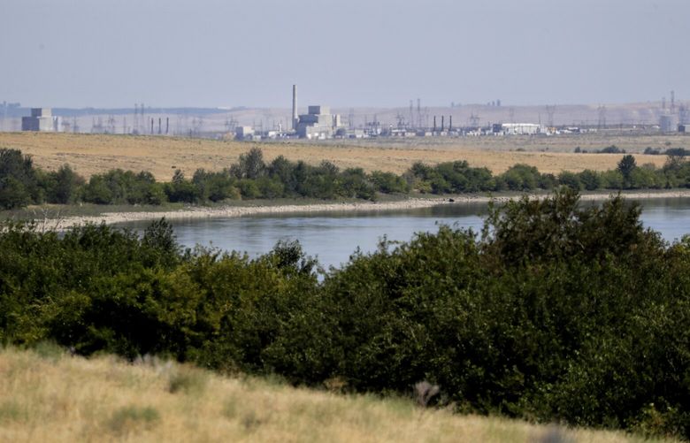 In this Wednesday, Aug. 14, 2019 photo, buildings on the Hanford Nuclear Reservation along the Columbia River are seen from the Hanford Reach National Monument near Richland, Wash. A handful of sites where the United States manufactured and tested some of the most lethal weapons known to humankind are now peaceful havens for wildlife, where animals and habitats flourished on obsolete nuclear or chemical weapons complexes because the sites banned the public and most other intrusions for decades. Hanford, where the cleanup has already cost at least $48 billion and hundreds of billions more are projected, may be the most troubled refuge of all. (AP Photo/Elaine Thompson) WAET213
