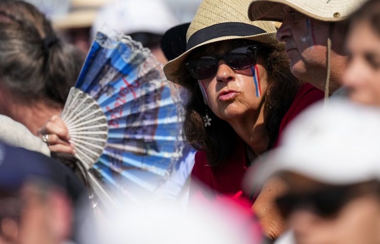 A fan tries to cool off during rowing competitions at the 2024 Summer Olympics, Monday, July 29, 2024, in Vaires-sur-Marne, France. (AP Photo/Lindsey Wasson) OLYAG201 OLYAG201