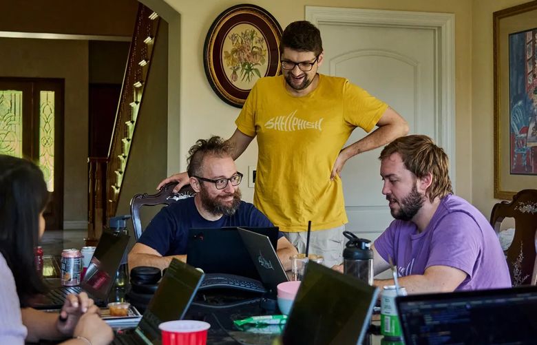 Yan Shoshitaishvili, a professor of computer science at Arizona State University, talks with Lukas Dresel and Wil Gibbs, co-captains of Team Shellphish, as they work at an Airbnb rental in Brea, Calif., on their entry to DARPA’s AI cyber challenge. (Philip Cheung for The Washington Post)