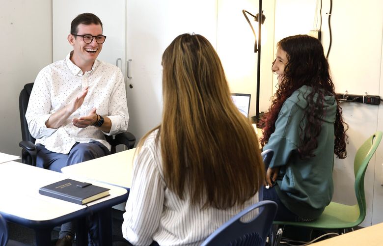Logan Parr, left, a 5th and 7th grade social studies teacher, meets with Maria Amezcua, center, and her daughter Gaby, 12, at Rainier Prep charter school in Seattle on Thursday, August 16, 2024.
