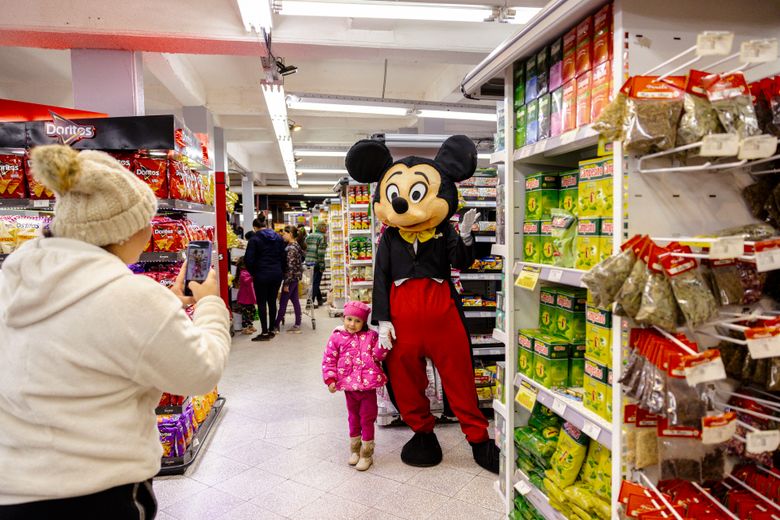 Mickey, company mascot and namesake of Mickey Paraguay, takes a photo with patrons at a grocery store in Luque, Paraguay, on Aug. 24, 2024. Mickey is famous for facing down Disney in Paraguay’s Supreme Court and as the family business turns 90, why is it still so popular? (Maria Magdalena Arrellaga/The New York Times)