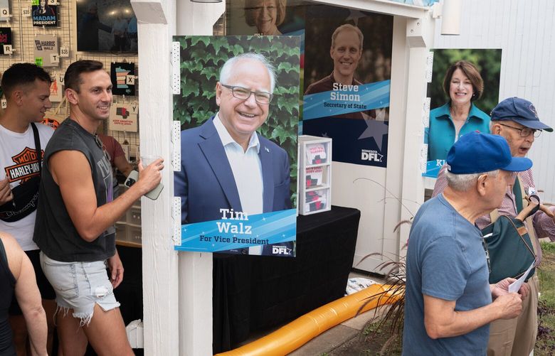 People pass by a poster featuring Minnesota Gov. Tim Walz (D) as they exit the Democratic–Farmer–Labor Party booth at the Minnesota State Fair on Aug. 23. MUST CREDIT: Tim Evans for The Washington Post