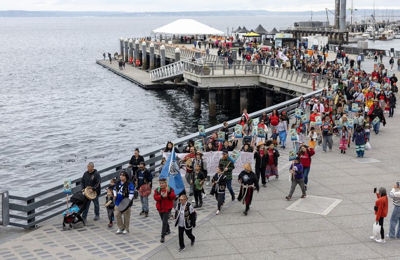 Люди маршируют от парка набережной Pier 62, празднуя День коренных народов в понедельник в Сиэтле. (Ник Уагнер / The Seattle Times)