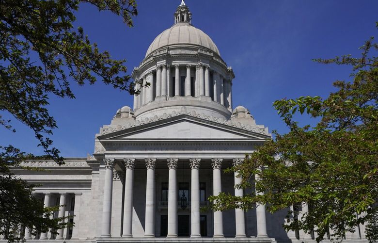 A person walks near the Legislative Building, Wednesday, April 21, 2021, at the Capitol in Olympia, Wash. On Wednesday, lawmakers were considering a proposed new tax in Washington state on capital gains that would be imposed on the sale of stocks and bonds in excess of $250,000. (AP Photo/Ted S. Warren)