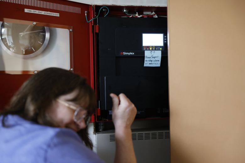 Leslie Galloway with Southwest Youth and Family Services turns off a fire alarm Sept. 10 that rings often.  (Karen Ducey / The Seattle Times)