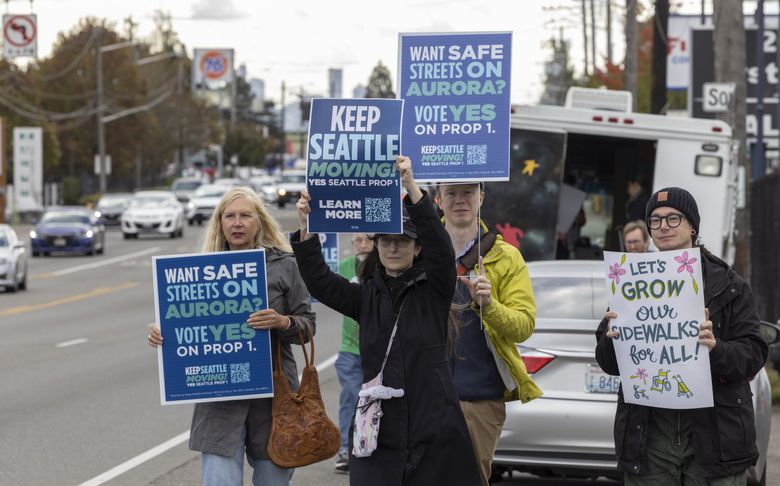 Адвокаты в области транспорта из трех организаций — Aurora Reimagined Coalition, Seattle Neighborhood Greenways и Keep Seattle Moving — на прошлой неделе прошлись по Авеню Аврора Норс, устанавливая и размахивая знаками в поддержку голосования «да» за Предложение 1. (Эллен М. Баннер / The Seattle Times)