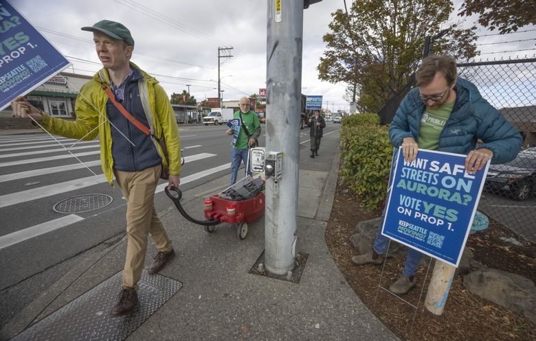 Гордон Паделфорд, исполнительный директор Seattle Neighborhood Greenways, слева, и Том Лэнг из Aurora Reimagine Coalition, присоединяются к другим сторонникам Пропозиции 1 в Сиэтле вдоль Северной Авроры, чтобы поддержать голосование 