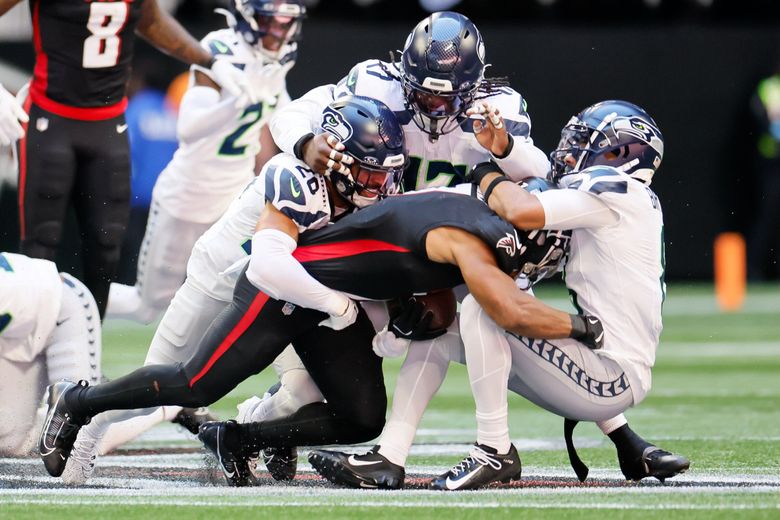 Seattle Seahawks safety Julian Love, left, linebacker Jerome Baker, center and cornerback Coby Bryant combine to take down Atlanta Falcons running back Bijan Robinson during the third quarter Sunday, Oct. 20, 2024 in Atlanta, GA. (Jennifer Buchanan / The Seattle Times)