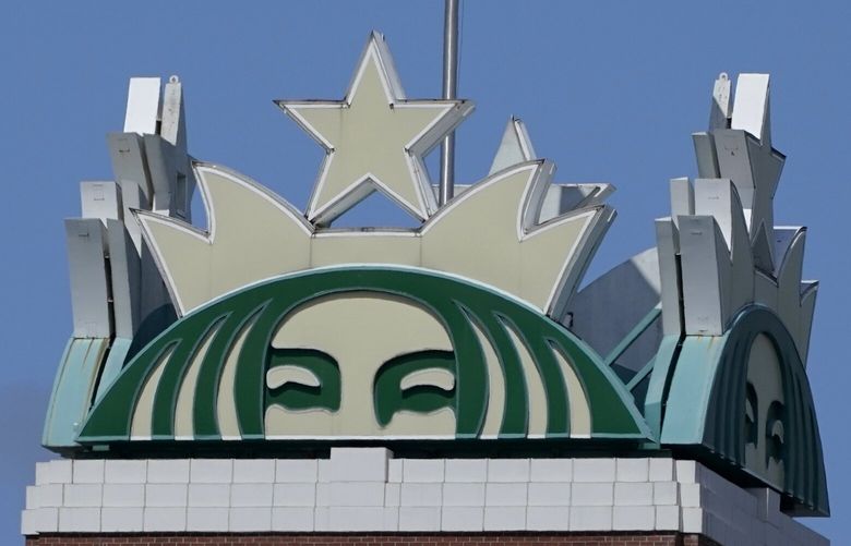 The U.S. flag flies above the Starbucks mermaid logo, Monday, April 26, 2021, at the coffee company’s corporate headquarters in Seattle. (AP Photo/Ted S. Warren) 