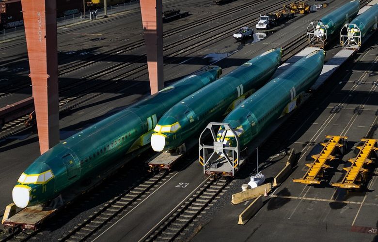 Boeing 737 MAX fuselages destined for the company’s Renton factory are stored on train cars south of the stadiums on Tuesday, Oct. 22, 2024 in Seattle. In the background is downtown Seattle. (Ken Lambert / The Seattle Times)