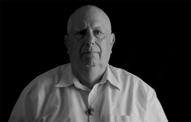 A black and white photo of an older man against a black background.